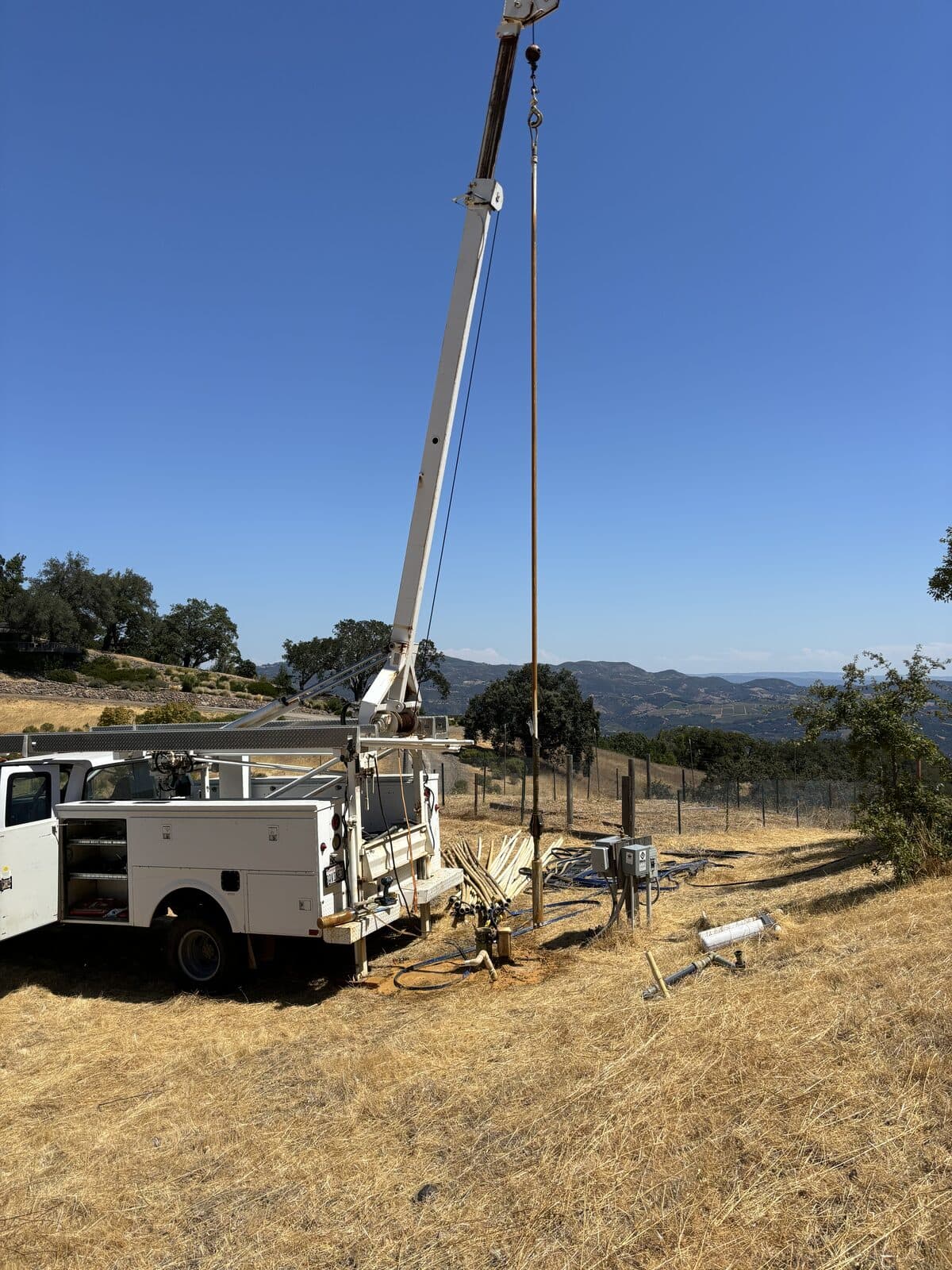 Service truck pulling pipe on a dry hillside