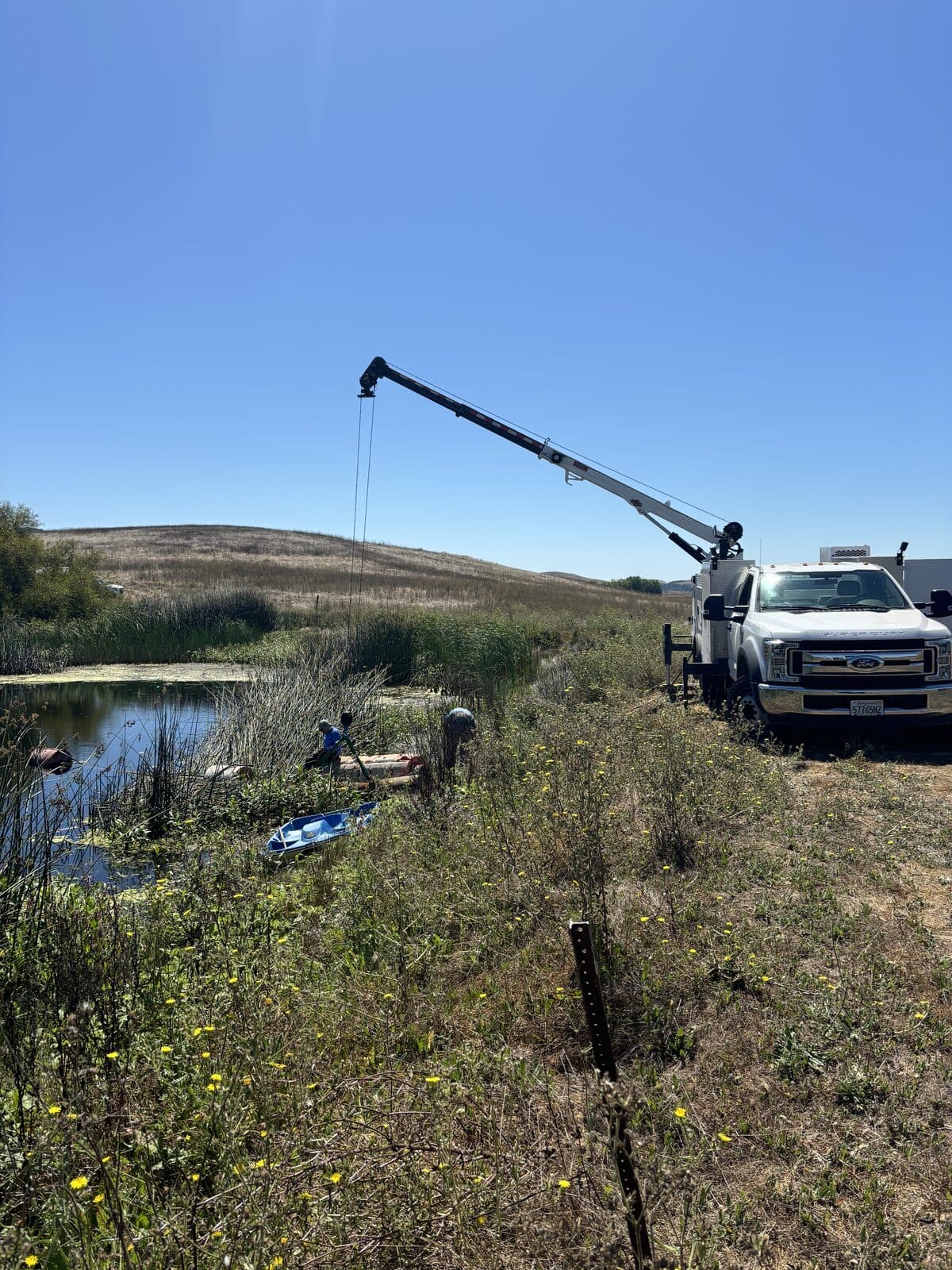 Crane truck working a well beside a pond